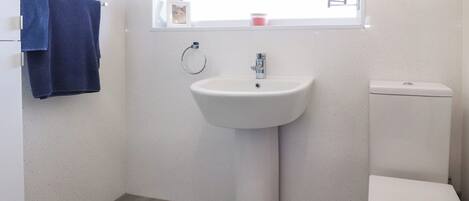 A bathroom with a white sink, a toilet, and a window above the sink.