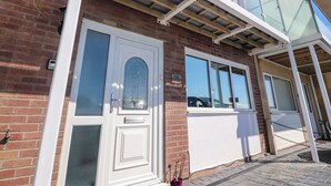 En toetages bygning med murstensfacade, vinduer med hvide rammer og en glasbalkon.