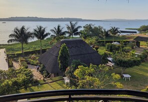 A thatched-roof structure surrounded by lush greenery and a body of water.