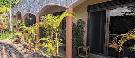Un edificio con fachada de piedra, entradas abovedadas y plantas en macetas.