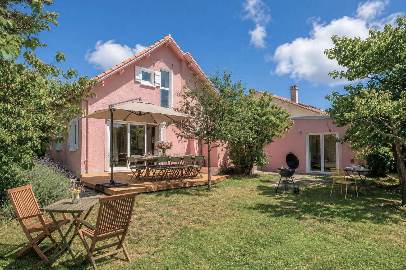 A pink house with a patio, outdoor seating, and a barbecue area.