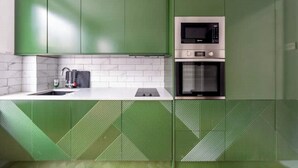 A modern kitchen with green cabinets, a microwave, and an oven. - Lovely Central London Apartment (London)