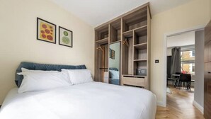 A bedroom with a large bed, a wardrobe, and a desk area. - Lovely Central London Apartment (London)