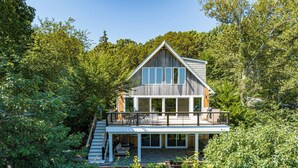 Et moderne hus med stor terrasse, omgivet af frodig vegetation.