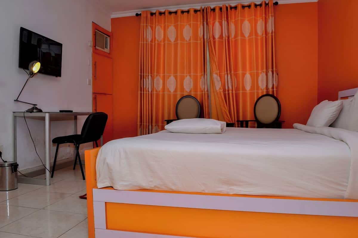 Habitación de hotel con cama, escritorio, silla y dos espejos redondos.