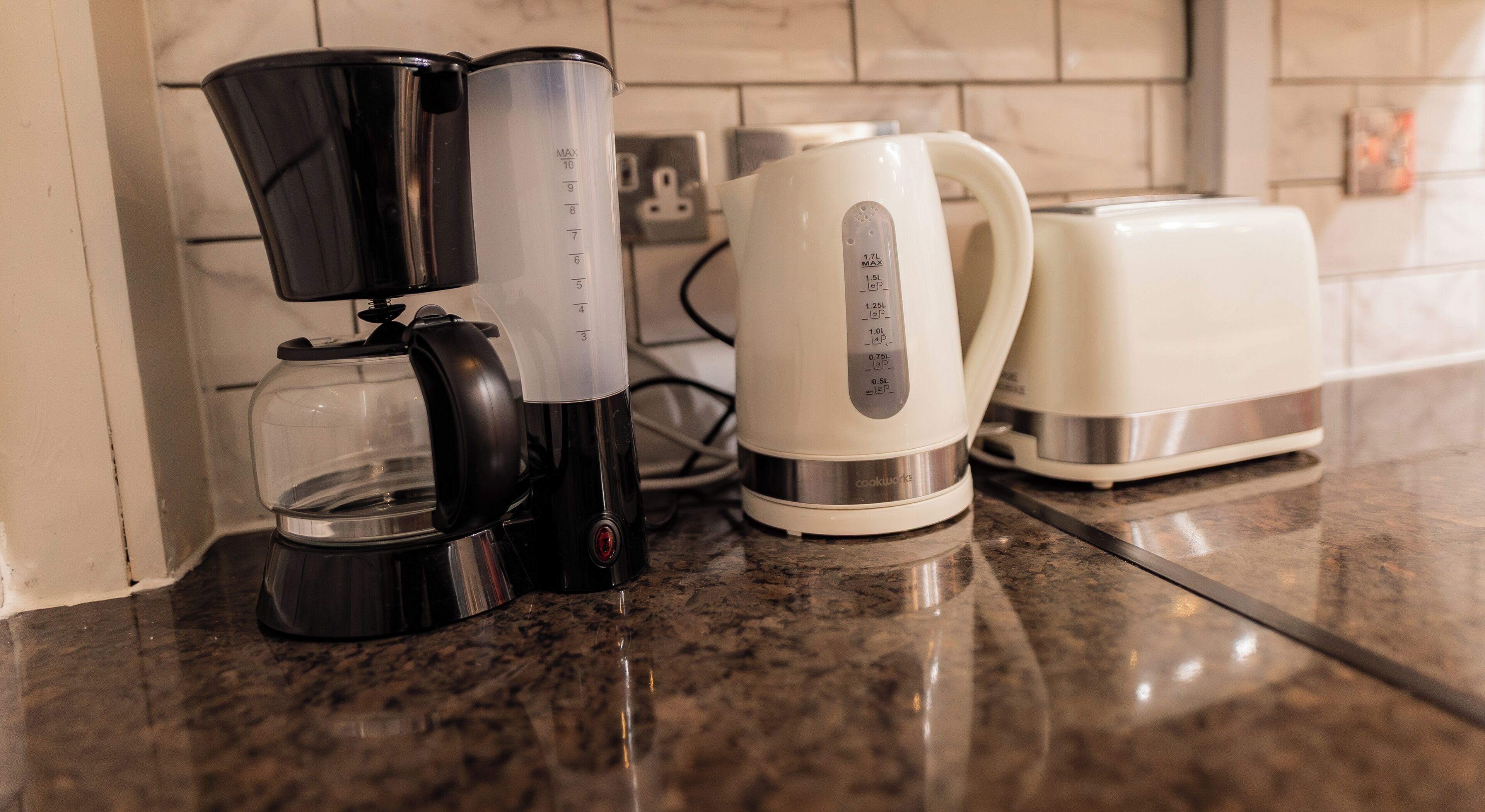 A kitchen with a coffee maker, a kettle, and a toaster on the counter.