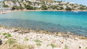 Un pueblo costero con edificios en una colina, con vistas a un mar azul y despejado.