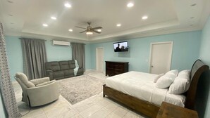 Un dormitorio con cama, sofá, televisión y ventilador de techo.