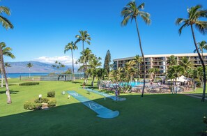 A golf course with a pool area, palm trees, and a building with multiple balconies.