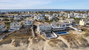 A coastal residential area with multiple beachfront homes featuring balconies, a swimming pool, and a sandy beach.