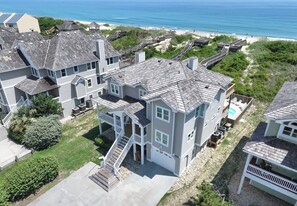 A large, multi-story house with a prominent front deck and a swimming pool. - Sunrise Dream - Nags Head MP 16, Oceanfront, Ocean View, Pool, Hot Tub, Sauna, Pets OK, Flex Stays (Nags Head)