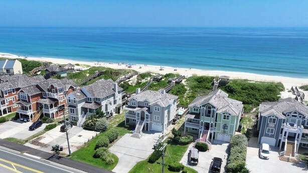 A coastal residential area with houses, a beach, and a clear view of the ocean. - Sunrise Dream - Nags Head MP 16, Oceanfront, Ocean View, Pool, Hot Tub, Sauna, Pets OK, Flex Stays (Nags Head)