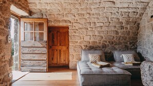Ein rustikaler Raum mit einer Steinsäule, einer Holztür und einem Sofa mit Kissen.