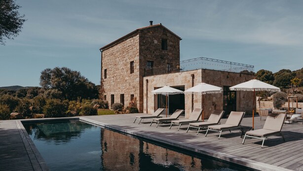Ein Gebäude aus Stein mit Pool und Liegestühlen.