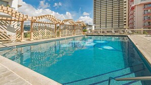 A swimming pool with a wooden fence, surrounded by buildings. - Ocean-Golf Course Couples Retreat at Island Colony Short Walk to the Beach (Honolulu)