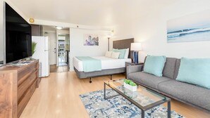A modern living room with a sofa, a bed, a coffee table, and a TV. - Ocean-Golf Course Couples Retreat at Island Colony Short Walk to the Beach (Honolulu)