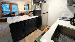 A modern kitchen with a central island, black cabinets, and a built-in stove.
