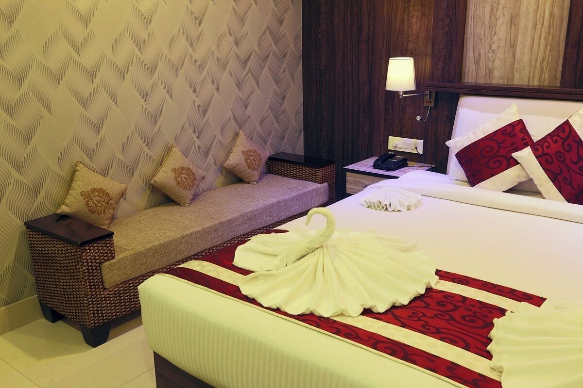Una habitación de hotel con una cama, un sofá, una mesita de noche y una lámpara.