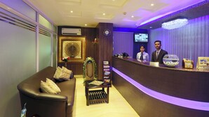 Un espace d’accueil comprenant un comptoir de réception, un canapé et un mur décoratif.