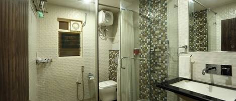 A bathroom with a glass shower enclosure, a toilet, a sink, and a mirror.