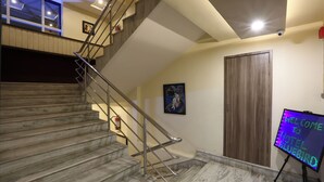 Un escalier avec des rampes en métal, une porte en bois et un panneau lumineux au néon accueillant les clients à l’hôtel.