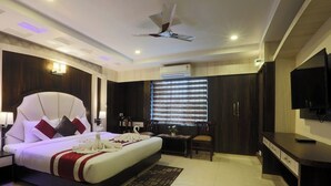 Une chambre d’hôtel moderne équipée d’un grand lit, d’un bureau, d’une chaise, d’un téléviseur à écran plat et d’un ventilateur de plafond.