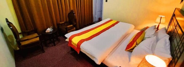 A hotel room with a bed, a chair, a small table, and a lamp. - Royal's Villa (Karimabad)