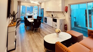 Una cocina moderna con armarios blancos, un comedor con mesa y sillas redondas, y un amplio ventanal con vistas al exterior.