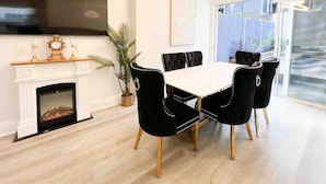 Un comedor moderno con chimenea, televisor de pantalla plana y un ventanal grande.