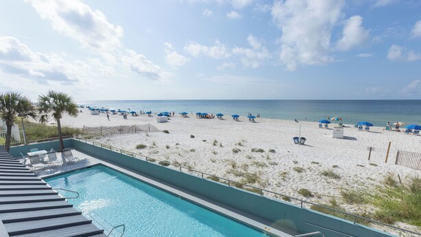 A pool adjacent to a beach with umbrellas and lounge chairs. - Westwind 204- 5 Star View! Gulf Front! Location X3! Desired Home! (Gulf Shores)