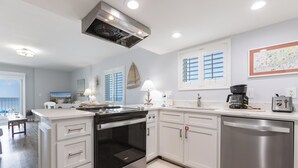 A modern kitchen with white cabinetry, a built-in oven, a dishwasher, and a coffee maker. - Westwind 204- 5 Star View! Gulf Front! Location X3! Desired Home! (Gulf Shores)