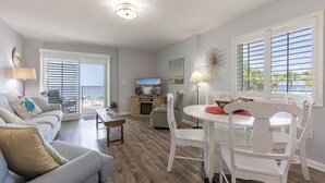 A living room with a sofa, a dining table with chairs, a TV, and a fireplace. - Westwind 204- 5 Star View! Gulf Front! Location X3! Desired Home! (Gulf Shores)