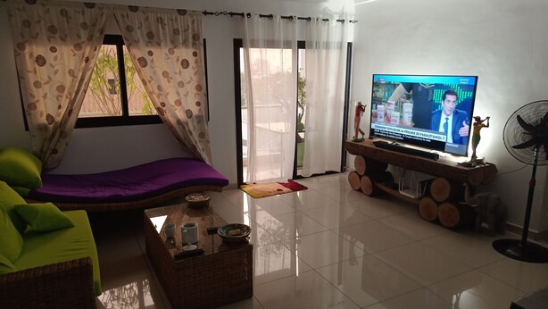 Ein Wohnzimmer mit einer Couch, einem Fernseher, einem Couchtisch und einem Ventilator.