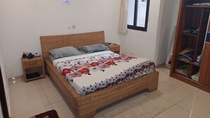 Ein Schlafzimmer mit einem Korbmöbelbett, einem Nachttisch, einem Kleiderschrank und einer Klimaanlage.