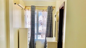 A bedroom with a bed, a dresser, a vanity, and a window with curtains. - Near the ocean  with Swimming pool ,Supermarket and ATM machine at the premises. (Dar es Salaam)