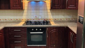A kitchen with dark wooden cabinets, a stainless steel range hood, a built-in oven, and a refrigerator. - Near the ocean  with Swimming pool ,Supermarket and ATM machine at the premises. (Dar es Salaam)
