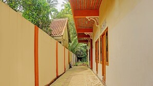 A narrow corridor with tiled flooring, beige walls, and a red-tiled roof. - OYO Life 92568 Penginapan Joglo Syariah (Kepanjen)