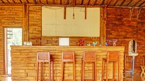 A rustic wooden bar area with a high ceiling and exposed beams, featuring a whiteboard, a sink, and several wooden stools. - OYO Life 92568 Penginapan Joglo Syariah (Kepanjen)