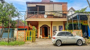 A two-story house with a balcony, a car parked in front, and a gate. - OYO Life 92568 Penginapan Joglo Syariah (Kepanjen)