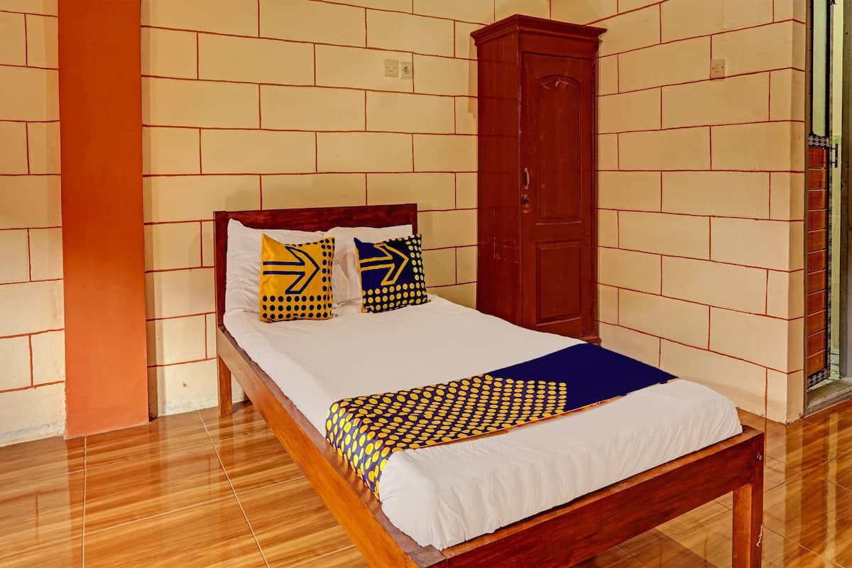 A neatly made bed with a patterned bedspread, a wooden headboard, and two pillows with geometric designs.