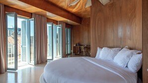 Een ruime slaapkamer met een groot bed, houten plafond en een bureau.