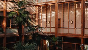 Een meerlaags atrium met glazen wanden, palmbomen en een open centrale ruimte.