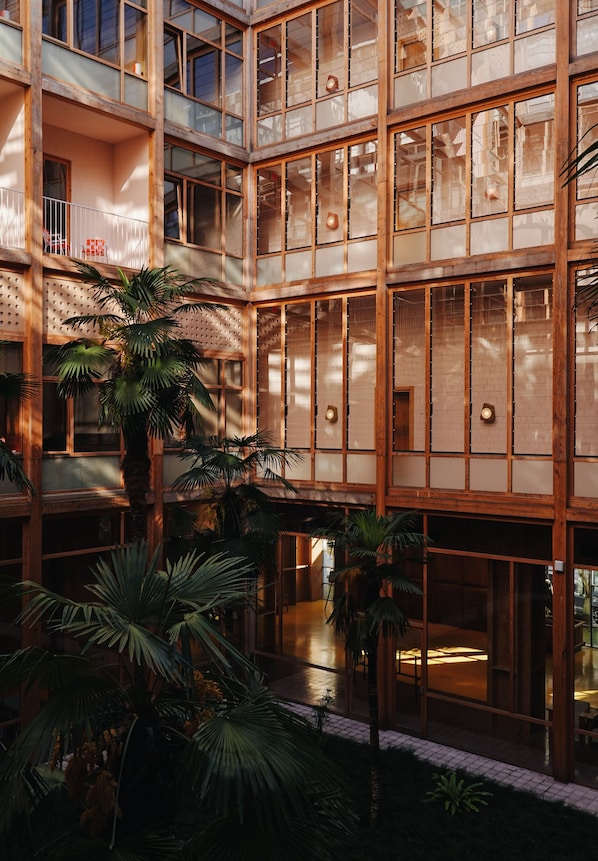 A multi-level atrium with glass walls, palm trees, and a central open space.