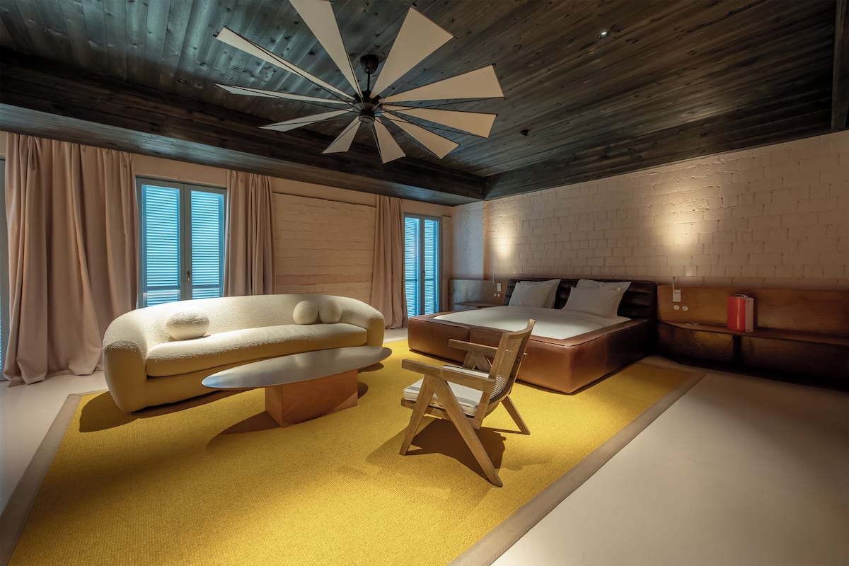 Un dormitorio moderno con techo de madera, una cama grande, un sofá y una silla.