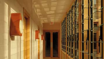 A corridor with wooden doors, glass partitions, and a tiled floor.