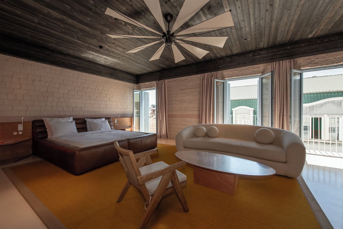 Habitación de hotel moderna con una cama grande, un sofá, una mesa de centro y vistas al exterior.