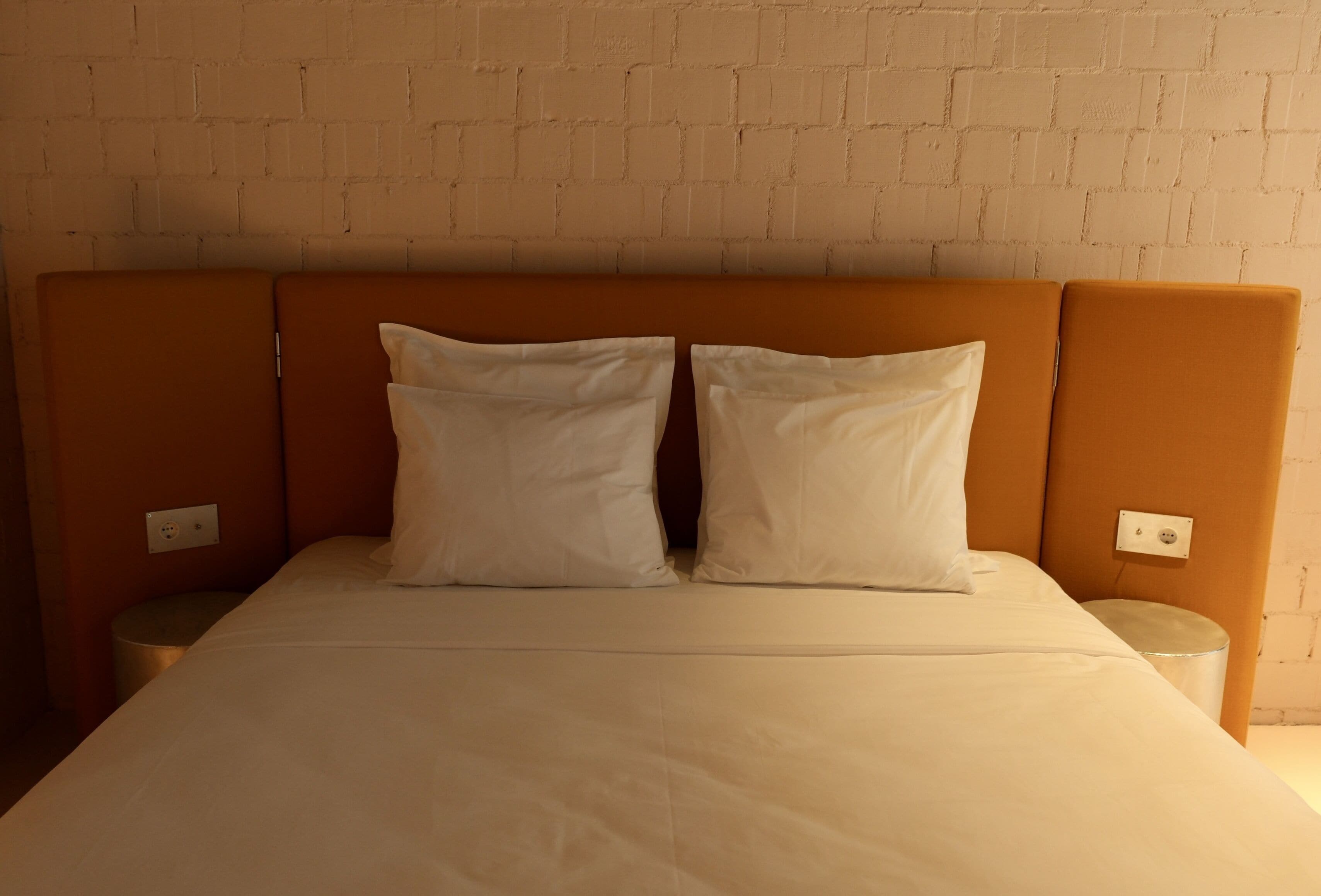 Een bed met hoofdbord, twee kussens en twee nachtkastjes.