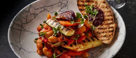 A plate of roasted vegetables and grilled chicken on a marble table.