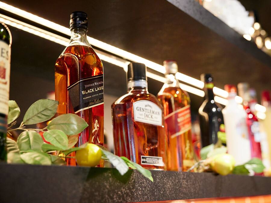 A row of liquor bottles on a shelf with a dark background.