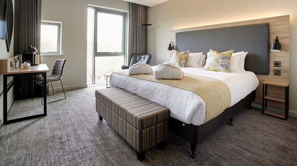 A hotel room with a large bed, a desk, a chair, and a bench. - Tŷ Newport (Newport)